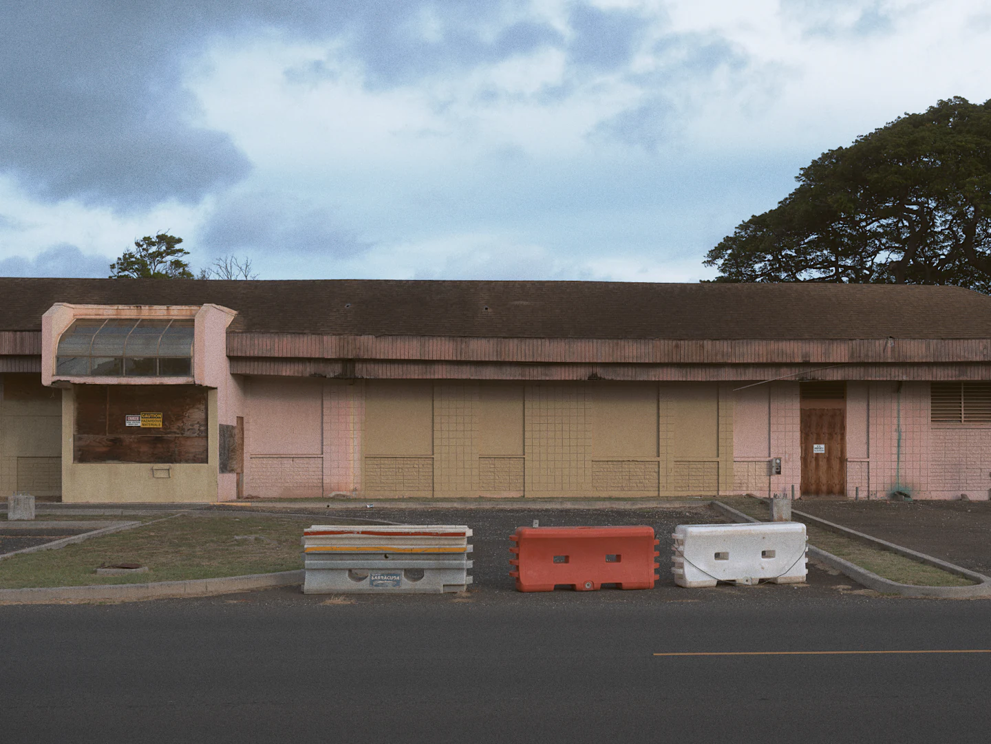 A shuttered pink building behind red and white road barriers, with Kodak Portra 160.