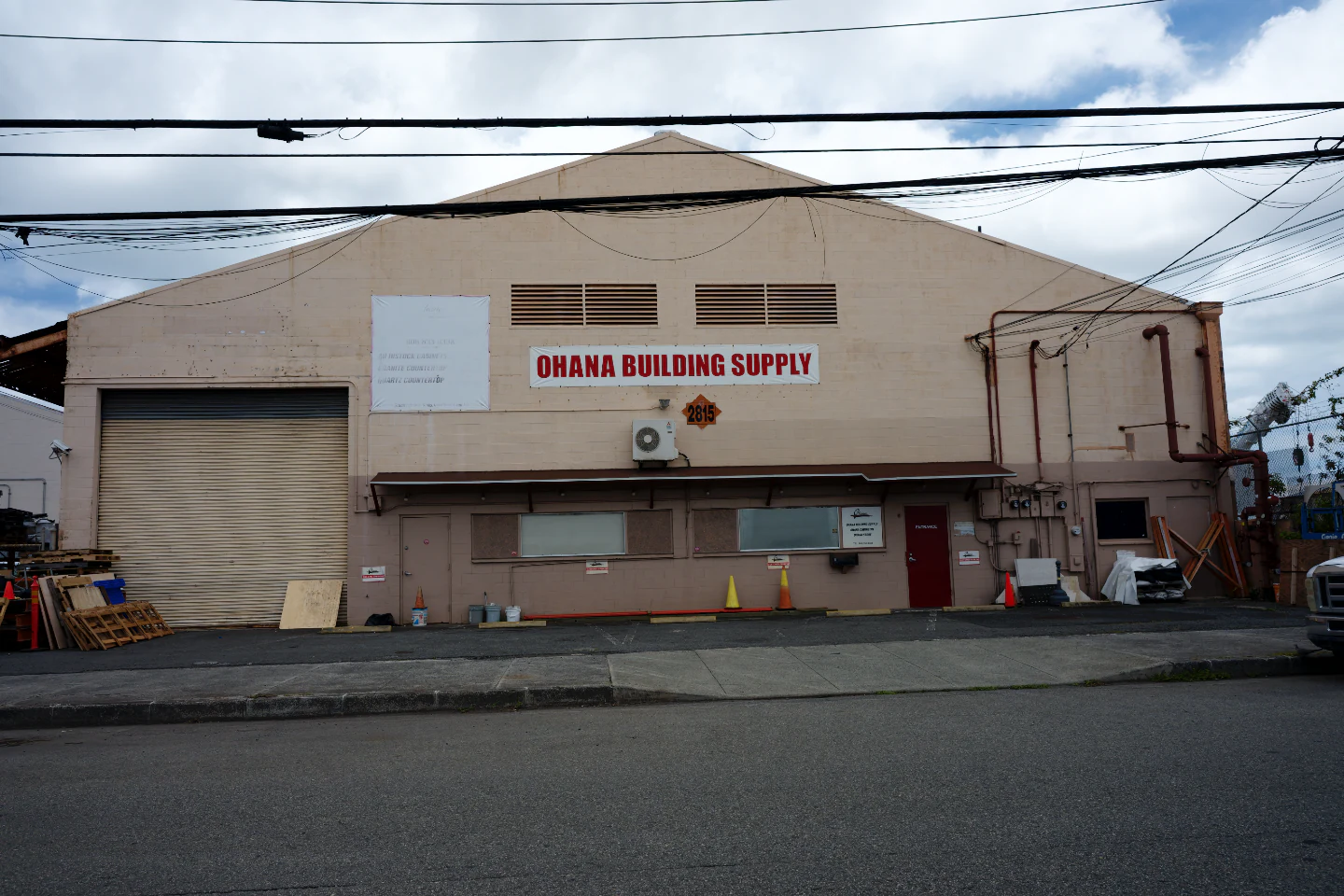 A pale pink warehouse under power lines as the RAW file opens, a little crooked, with no film.